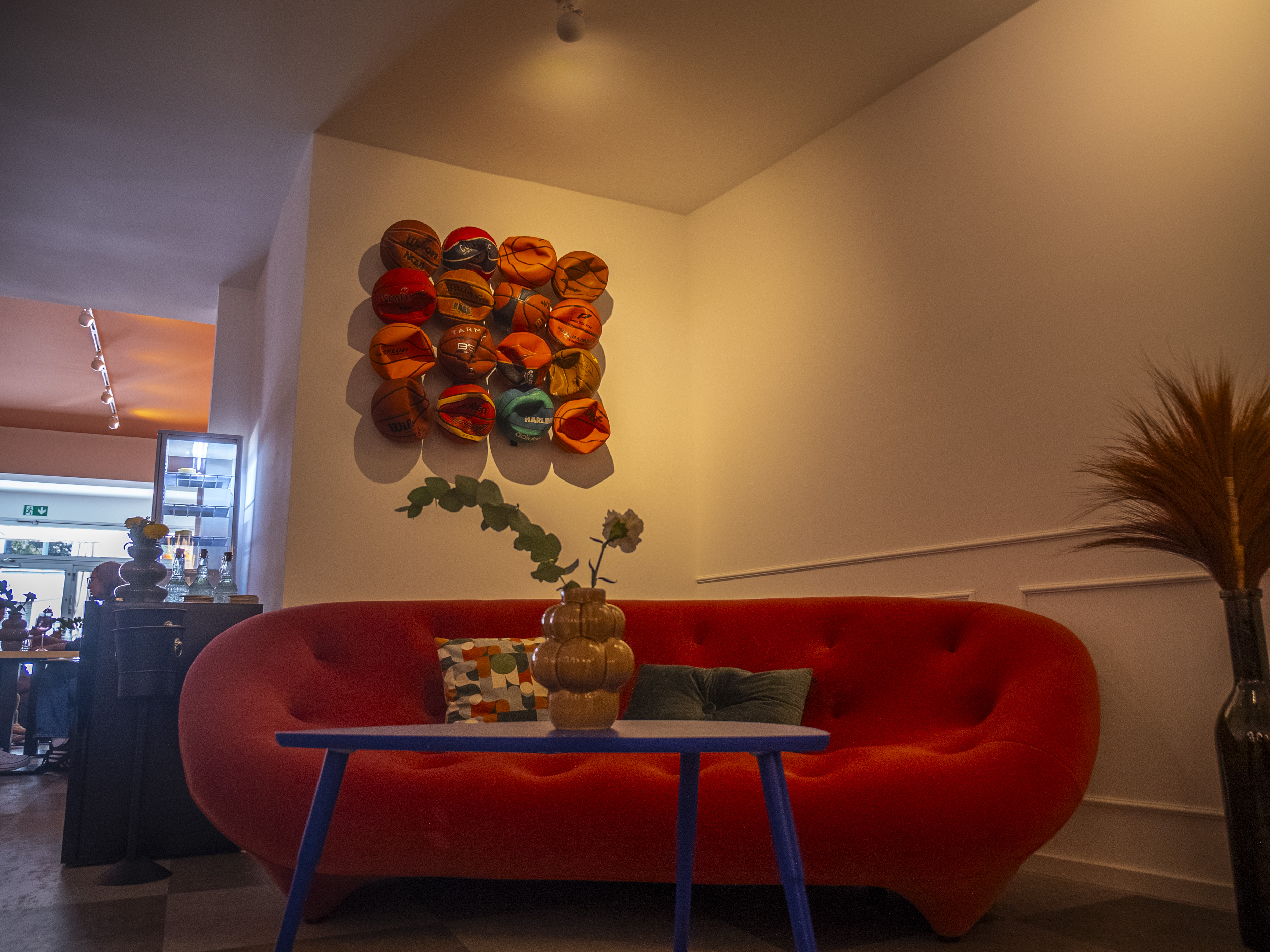 Ein rundes Stoffsofa steht in einer Zimmerecke mit roter Wanddeko.